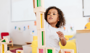 Preschool child building a tall block tower during play-based learning in a bright Willowdale classroom
